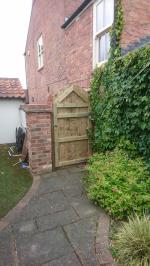 Framed, ledged and braced gate finished in pressure treated gravel boards fitted vertically with an arched top