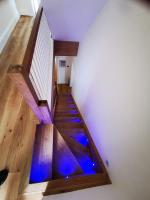 Glass and oak staircase with blue string lights on alternate steps that activate when you walk on the stairs
