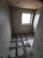 Bathroom being refurbished, grouting floor tiles
