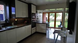 Cream gloss kitchen with wenge worktops on diagonally fitted cream slab tiles, oak bi-fold doors, vaulted ceiling