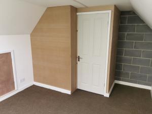 Garage loft landing having partition stud-walling built, paneled out in mdf and insulated with four-panel door