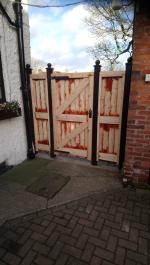 Framed, ledged and braced redwood tongue and groove gate and flanking panels in a gothic style