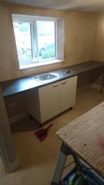 cream cupboards, worktop and sink being installed for utility
