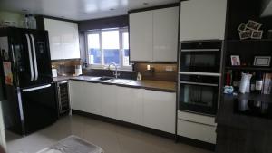 Cream gloss kitchen with wenge worktops on diagonally fitted cream slab tiles