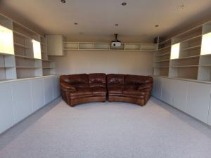 Cinema room formed from ivory paneling with base cupboards, shelves and feature display boxes, lit with led spots