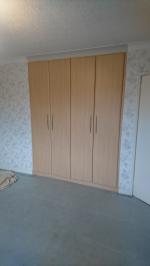 Beech paneled wardrobe built into bedroom alcove